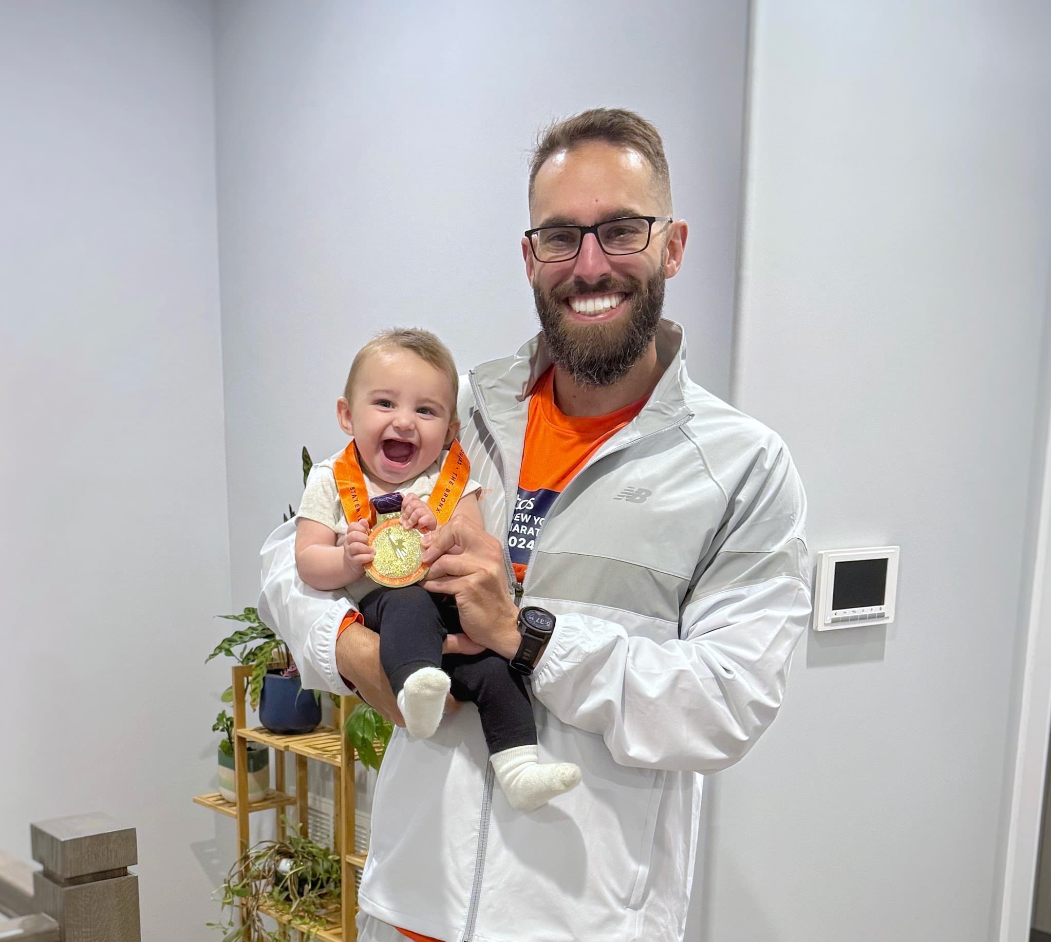 Tony Segreto holding his daughter and his NYC Marathon finisher medal.